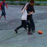 チャーミーコーチとボールを取り合う奈◎選手。後方は雨男？！